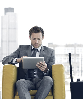Man sitting in a chair looking at tablet.