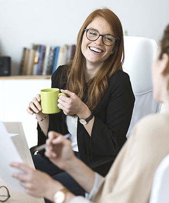 Woman with mug smiling at colleague