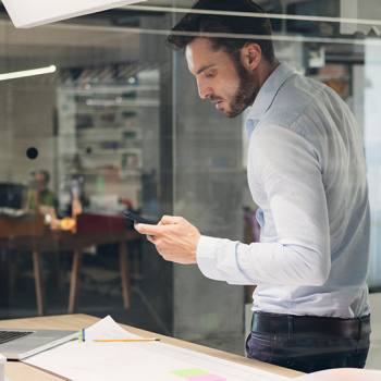 Print on the go man using a smartphone while standing over desk