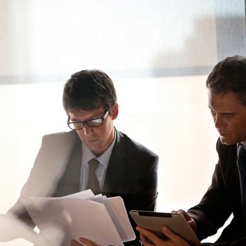 Servicios financieros Two men looking at paperwork and tablet
