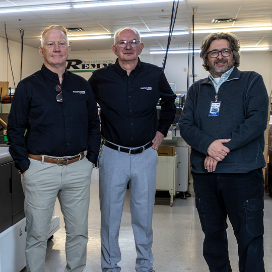 Inkjet printers are a game changer. three production print professionals smiling by a commercial printer