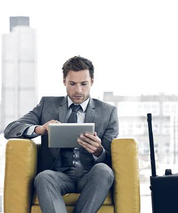 Man sitting in a chair looking at tablet.