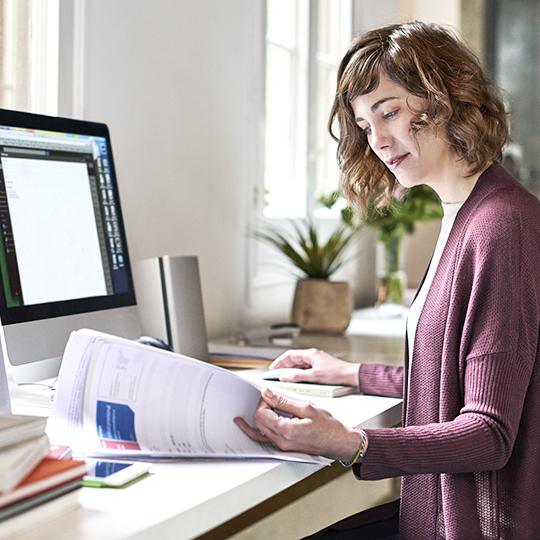 Control cost & Guest Printing Woman looking at paperwork in front of computer.